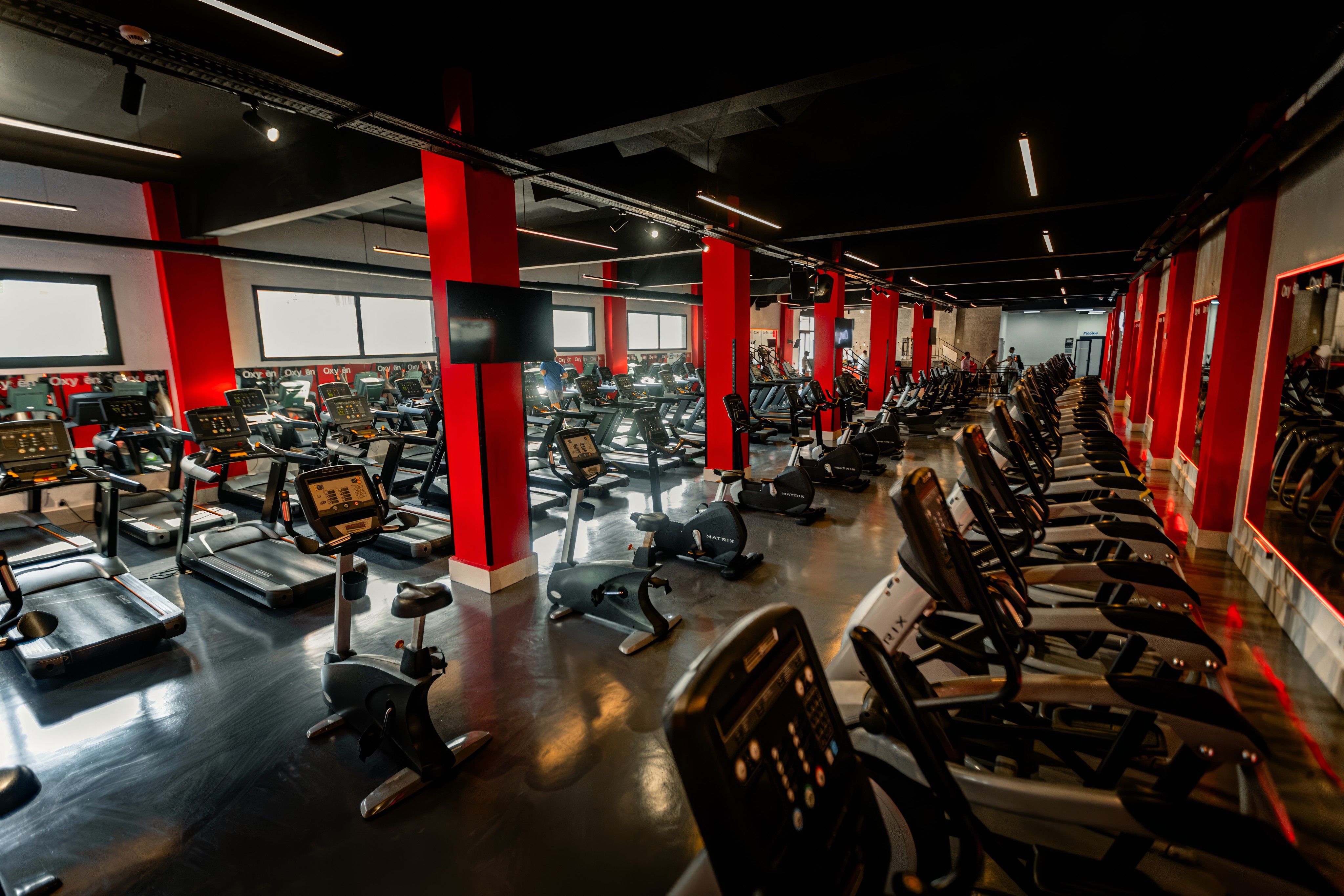 Plateau cardio du club Oxygen, lumières rouges et baies vitrées